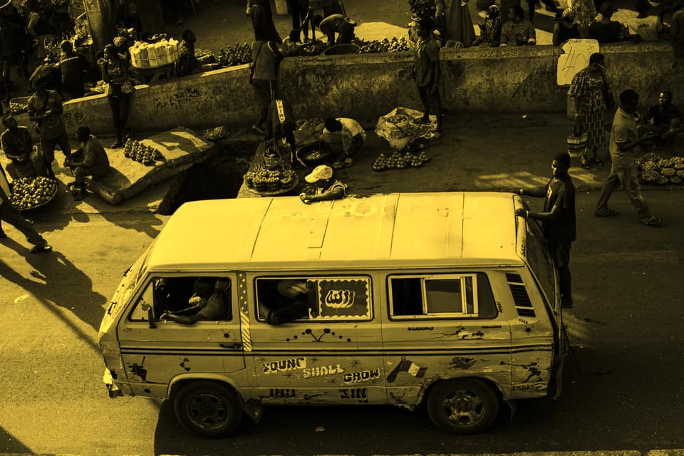 A danfo seen from above, edging through a busy Lagos market