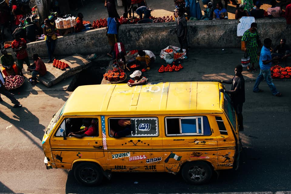 A danfo seen from above, edging through a busy Lagos market