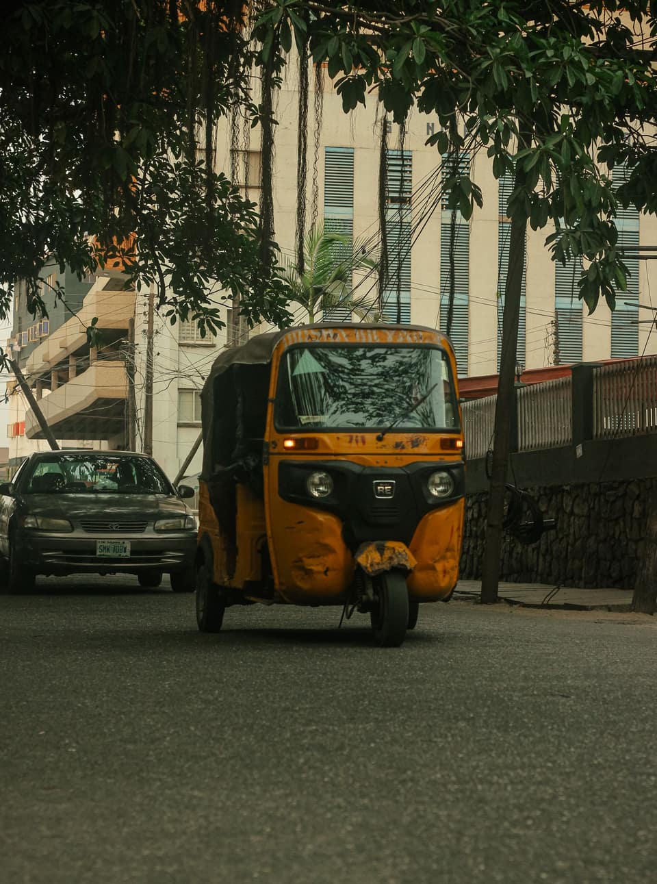 A yellow keke seen from the front on a Lagos road