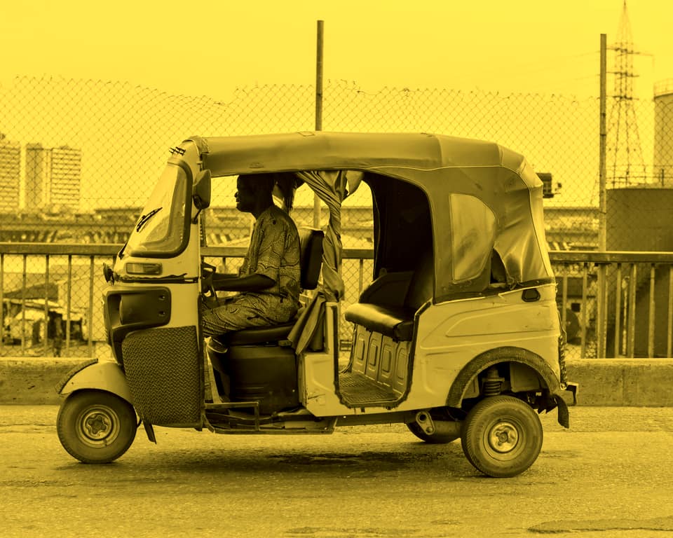 A yellow keke with a grey canopy on a Lagos street