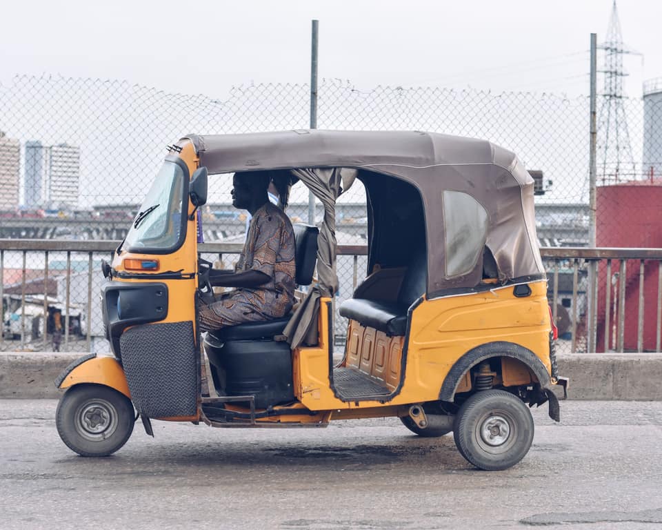 A yellow keke with a grey canopy on a Lagos street