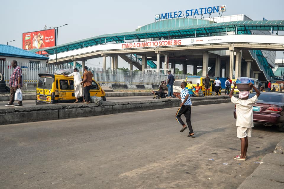 Mile 2 station with yellow buses and commuters