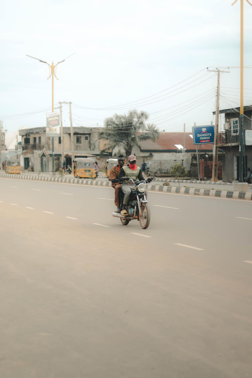 An okada rider carrying a passenger on a Lagos road